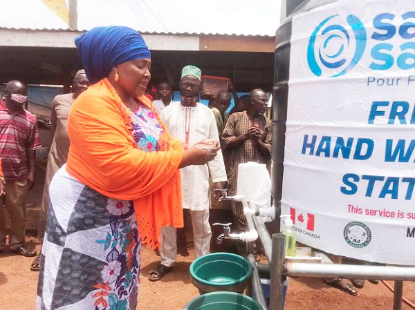 Hajia Ayishetu Seidu, the Savelugu Municipal Chief Executive,   demonstrating how to wash the hands after the inauguration of one of the seven handwashing stations provided by Sama Sama Ghana