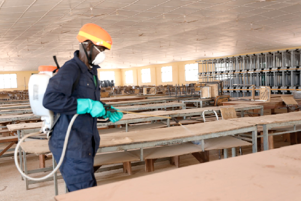 A staff member of Zoomlion disinfecting the dining hall of the students