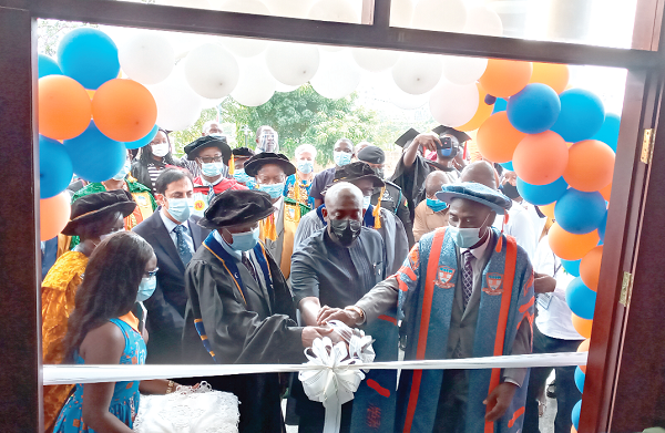  Mr Kojo Oppong Nkrumah (middle) being assisted by Prof. Kwamena Kwansah-Aidoo (right), Rector of GIJ, to cut the tape to inaugurate the building complex on the institute’s new campus located at Dzorwulu in Accra 