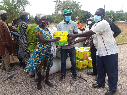 The Head of Programmes and Advocacy of the PFAG,Mr Charles Nyaaba(middle wearing cap) being supported by Mr Hafiz Muntaka,the Programme Manager of Economic Justice of Oxfam(first right) presenting a carton of cooking oil to a beneficiary,Miss Ama Alinyorke