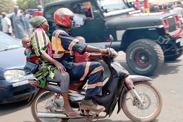 A man carrying his wife and two children on a motorbike on the streets of Tamale. INSET: Some young men sitting on a bus on a  street in Tamale. Pictures: SAMUEL TEI ADANO 