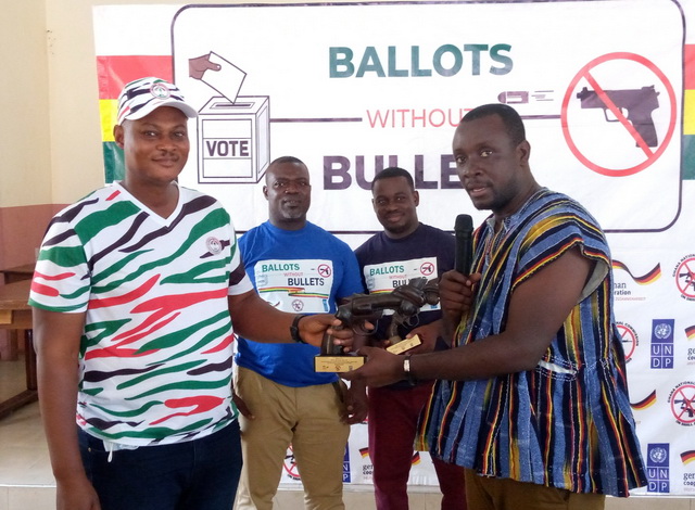 NDC's Michael Adu-Sei (Left) receiving a gift from NPP's Charles Acheampong (Right) and vice versa as demanded by the Executive Secretary of the Small Arms Commission, Mr Jones Applerh who looks on together with another official of the commission.
