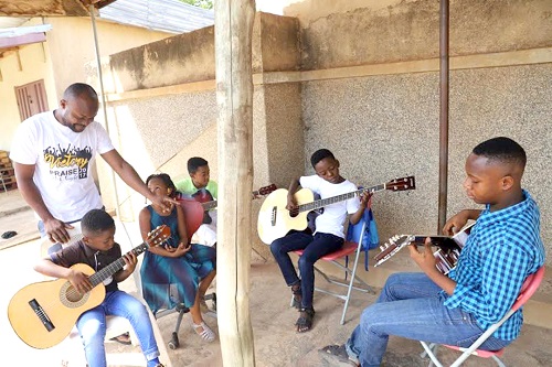  Pastor Acheampong (standing left), supervising the pupils during one of their music sessions.