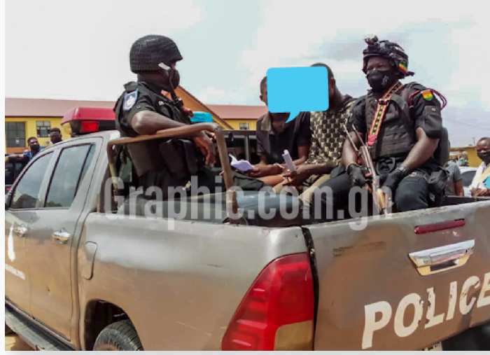 The suspects (faces covered) with the police after their first appearance in court
