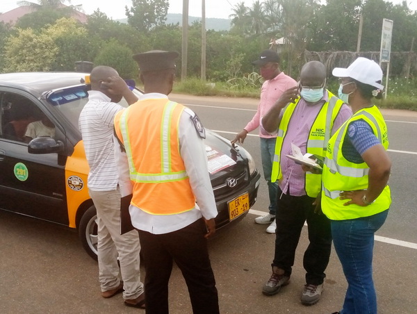 Mrs Esther Konadu Ofori, Eastern Regional Manager of NIC (standing akimbo) and other officials examining the authenticity of a taxi cab’s insurance.