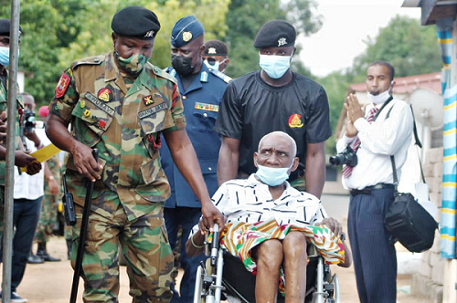 Prince Amartey (in wheelchair) being accompanied to the inauguration ceremony by an army officer 