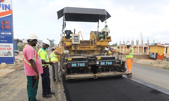 Mr Dan Phillips (left), the Site Engineer in charge of the project, and Mr Mamudu Kagifah (2nd left), the Supervisor, monitoring the asphalt surface installation on the road at Nyanyano, near Kasoa. Picture: GABRIEL AHIABOR
