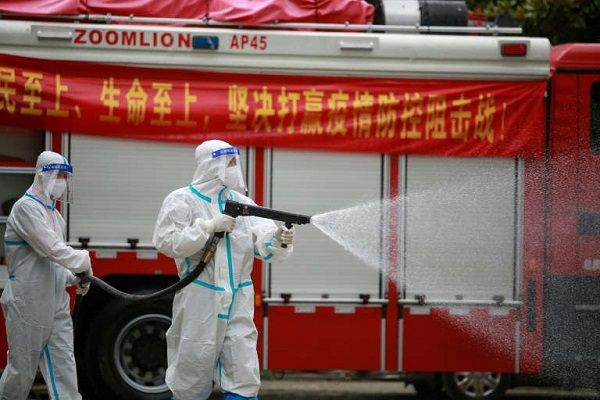 A firefighter wearing protective gear against the spread of Covid-19 coronavirus sprays disinfectant in a residental area in Yangzhou, in China's eastern Jiangsu province