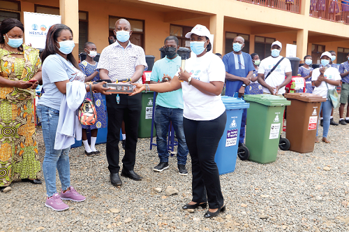 Ms Debora Kwablah (right),  Corporate Communications and Public Affairs Manager, Nestle Ghana, presenting some sanitation equipment to Mr Ransford Narh Narteh (middle), Coordinator, Science, Technology, Mathematics and Innovation Education, and a representative of the school
