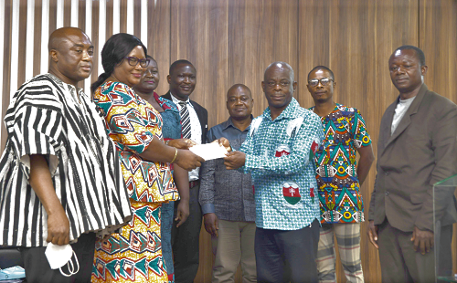 Mr Raphael Kwashie (3rd right), Principal of the St Francis College of Education, Hohoe in the Volta Region, receiving a cheque for GH¢22,000 from Ms Phillipa Larsen (2nd-left), the President of GNAT. With them are Mr Thomas T. Musah (left), General Secretary of GNAT, and representatives of the beneficiary institutions
