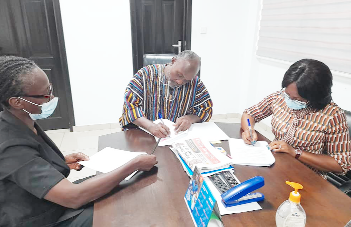 Mr. Robert Patrick Ankobiah (middle), Chief Director, Ministry of Food and Agriculture, and Ms. Sally Ofori Yeboah (right), CAMFED National Director, signing the MoU, while Ms. Paulina Addy, WIAD Director, looks on.