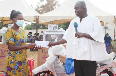 Mr. Emmanuel Kofi Agyeman, DCE for Dormaa East Assembly (right), presenting cash in an envelope to one of the beneficiaries