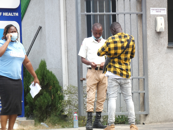  A security person inspecting the vaccination card of a visitor at the MoH Head Office. PICTURE: ELVIS DOWUONA