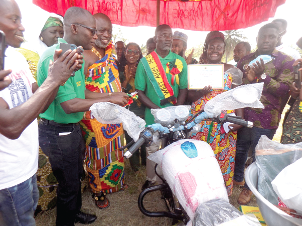Mr Seth Oduro-Boadu (left), the West Akyem Municipal Chief Executive, being assisted by Barima Aboagye Tanoh I (2nd from left), Chief of Afranse, to present the Municipal Best Farmer prize to Mr Ishaque Asirifi Amoah