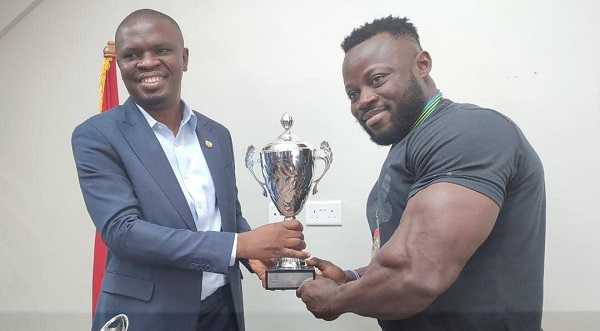 Mr Mustapha Ussif(left), the Minister of Youth and sports, receiving a trophy from Godwin Frimpong, Black Muscles Captain