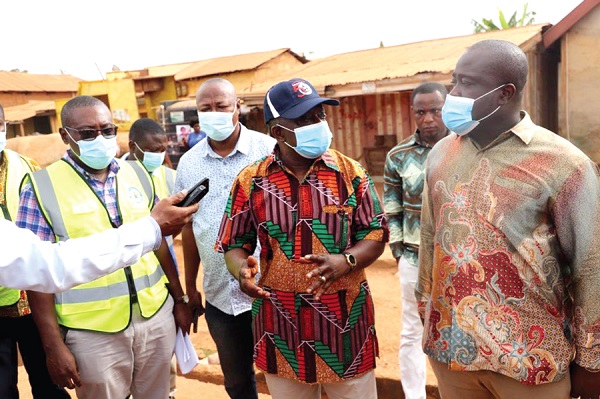 Mr Simon Osei Mensah (in cap), speaking to the media during a tour of some  ongoing road projects in the Ashanti Region. With him include Mr Samuel Pyne (arrowed), MCE of Kumasi, and Nana Poku Agyemang (right), the Urban Roads Director of the KMA.