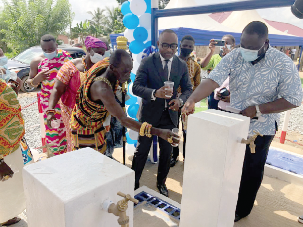 Mr Sops Ideriah (2nd from right), Managing Director of GOS Company Limited in charge of Nigeria and West Africa, and Nana Ntsin Kofi II (left), Divisional Chief of Aboade, being served with water from the borehole 