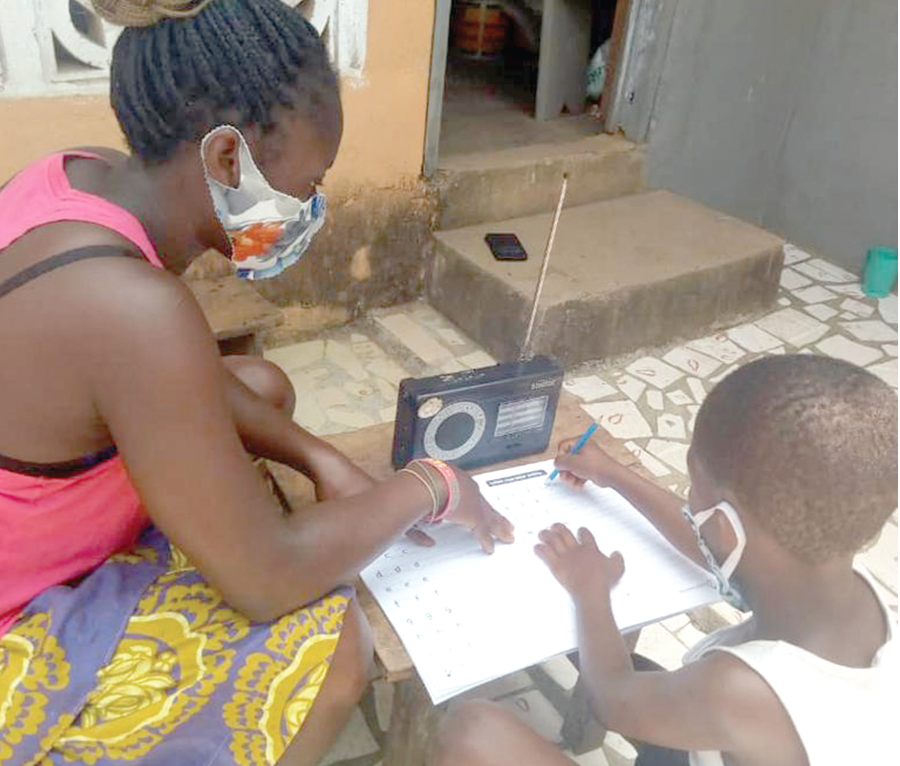 A parent helping the child in a writing exercise during one of the Literacy programmes on the radio