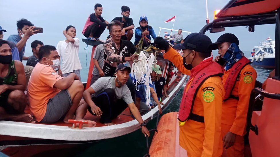 Local fishermen retrieve suspected debris and hand it to search and rescue teams