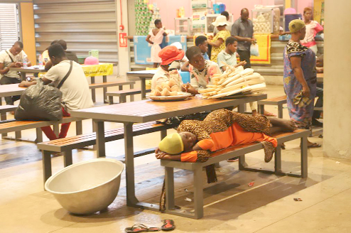 A head porter taking a nap at the seating area at the new Kejetia Market while others display their merchandise on the tables for sale. Pictures: EMMANUEL BAAH