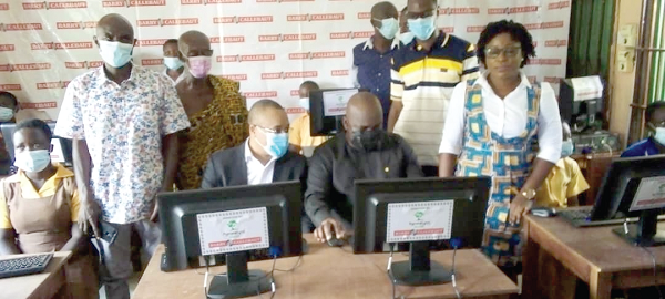 • Mr Michael Okyere Kofi Baafi (seated right), MP for New Juaben South, and Mr Mamadou Ly (seated left), Managing Director of the Nyonkopa Cocoa Buying Company Limited, demonstrating how the pupils should operate the computers at Densuano  