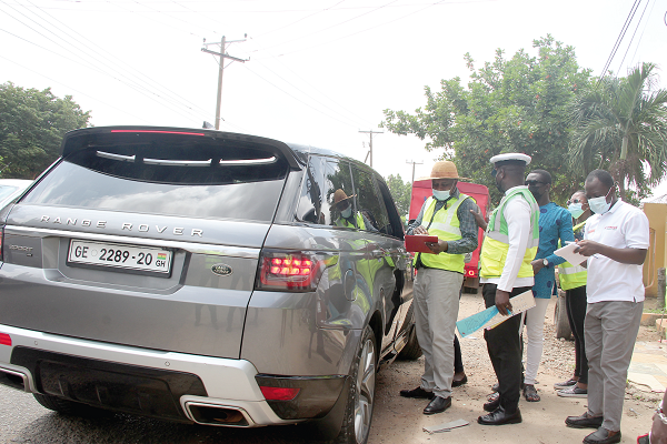 Mr Courage Verleeson Doh (left), an Enforcement Compliance Officer, DVLA, with the help of the police checking for fake number plates and expired roadworthy certificates on the Spintex Road