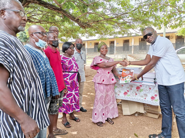 •  Mr Bright Atiase (right),  President of DEPOSA, handing over the books to Mrs Vivian Agbesi Amenya, head teacher of the Peki Dzake E. P school