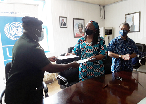 Major General Francis Ofori (left), KAIPTC Commandant, and Dr Angela Lusigi (2nd right), UNDP Resident Representative, exchanging documents on the project as Mr Tsutomu Himeno (right), the Japanese Ambassador to Ghana, looks on