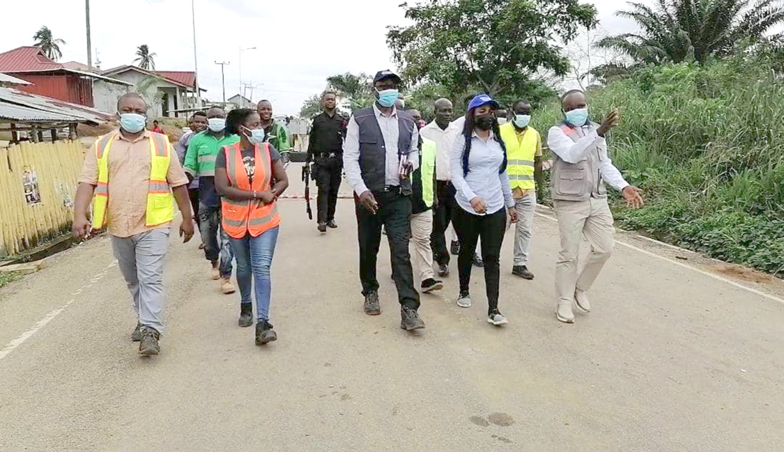 Mr Kwesi Bonzoh (right), Ellembelle District Chief Executive, explaining the extent of damage on the road to Mrs Mavis Nkansah-Badu (2nd right), Deputy Minister of Roads and Transport, and other members of the team