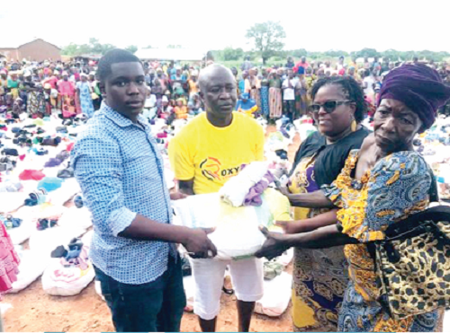 Mr Konlan, (middle) presenting some food items to a beneficiary (right). Assisting him are his son and wife