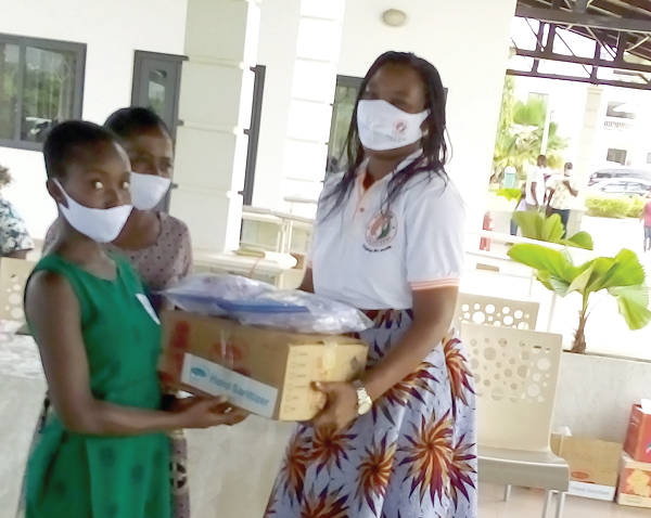   Ms Lydia Tsotsoo Odai-Tettey (right), Country Coordinator of Rescue Volunteers Ghana, presenting PPE to a representative of the Kpong Evangelical Presbyterian School    