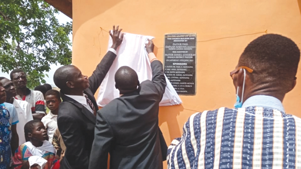 Pastor Paul Dapaah Asiakwan (middle), President of North Ghana Mission of the SDA, assisted by Pastor Daniel Gyemerah, the Salaga District sda pastor, to unveil the plaque to inaugurate the church building