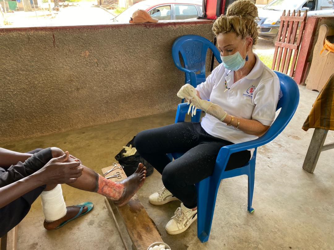 A foreign volunteer dressing the wound of a cured lepe