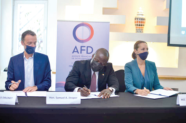 Mr Samuel Abu Jinapor (middle), the Minister of Lands and Natural Resources, signing the agreement. Looking on are Ms Ann-Sophie Avé (right), the French Ambassador to Ghana, and Mr Nicholas Drunet of Noe, an NGO