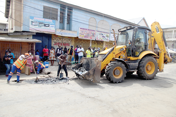 Some volunteers at the clean-up exercise, with a backhoe loader collecting waste