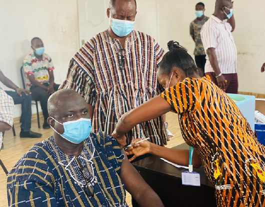 Mr. Samuel Nii Adjei Tawiah (seated) being vaccinated by a health worker