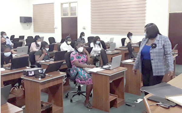 Personnel receiving calls from concerned parents and students as Ms Cassandra Twum Ampofo (right), the PRO of the GES, observes the exercise