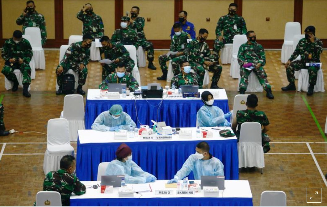 FILE PHOTO: Indonesian soldiers sit as one of them receives a dose of China's Sinovac Biotech vaccine for the coronavirus disease (COVID-19), during a mass vaccination program at a sport hall in Jakarta, Indonesia, March 10, 2021. REUTERS/Ajeng Dinar Ulfiana