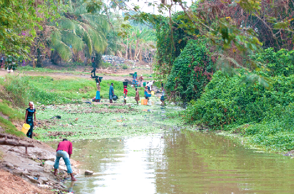 Some people drawing water from a polluted river