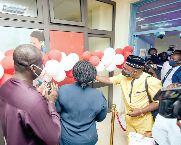 Mr David Afflu (right), General Manager, GB Foods Ghana, cutting the tape to open the Wellness Centre (inset). Looking on are Dr Ebenezer Oduro Mensah (left), Medical Superintendent in charge of the hospital, and Ms Selorm Kutiakor (back to camera), Municipal Health Director, Kwabenya 