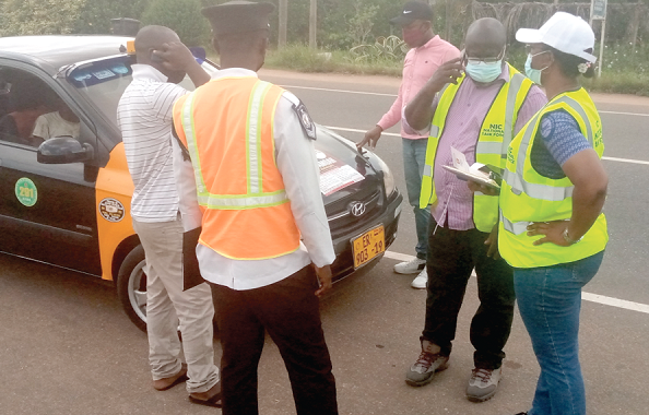 • Mrs Esther Konadu Ofori, the Eastern Regional Manager of NIC (right) and other officials checking the authenticity of a taxi cab’s insurance