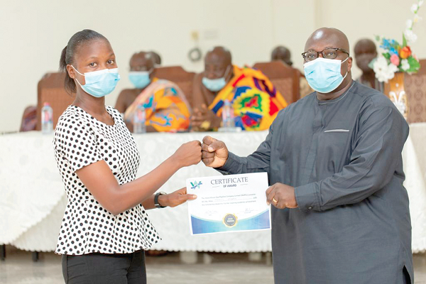 • Dr. Doku (right) presenting a certificate signifying the award of scholarship to a beneficiary