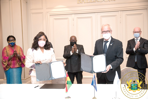 Ms Shirley Ayorkor Botchwey, Minster of Foreign Affairs and Dr Werner Hoyer, President of the EIB displaying copies of the agreement while President Akufo-Addo (middle) applauds