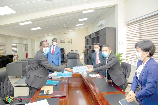 Mr Benjamin Kofi Gyasi (left), Chief Director of the Ministry of Education, exchanging documents with Mr Tommy Zhou while Dr Yaw Osei Adutwum (2nd left), Minister of Education, looks on