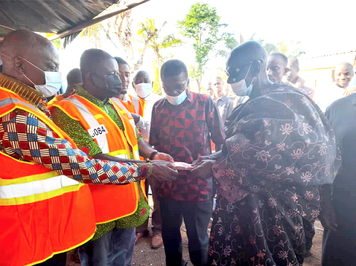 Nana Agyemang Prempeh (2nd left), Director-General of NADMO, and Mr George Yaw Boakye (left), Ahafo Regional Minister, jointly presenting the GH¢20,000 to Nana Yaw Boakye (right), Chief of Amanfrom
