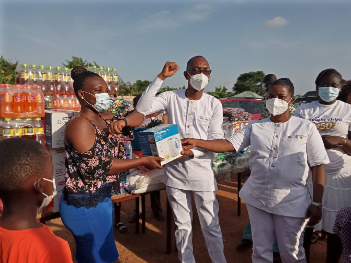    Rev. King-Bi Adjei (middle) presenting an item to Madam Jacqueline Emefa (left), a Social worker at the village. Looking on is Rev. Adjei's wife 