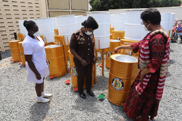 Mrs Sophia Akuffo, (right), Chairperson of the National COVID -19 Trust Fund demonstrating the use of the hand washing machine to the Ghana Prison Service.