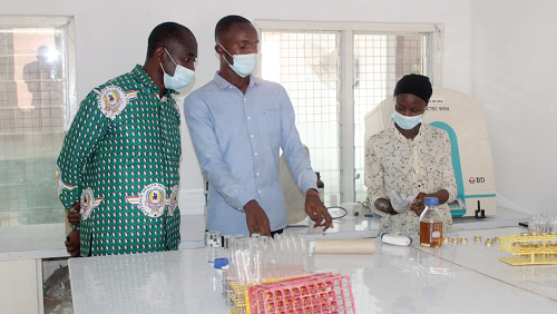  Dr Patrick Odum Ansah (left),  acting Director of the centre, interacting with some staff of the centre conducting some tests