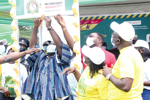 Mr Kwaku Ofori Asiamah, Minister of Transport,  cutting a ribbon to launch the NRSA Stay Alive campaign in Accra. Looking on are some officials of the NRSA and other dignitaries. Picture: Patrick Dickson 
