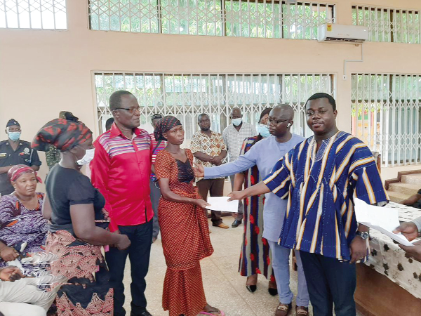 Mr John Ntim Fordjuor (right), Deputy Education Minister, presenting some money to the bereaved families. Behind him is Prof. Opoku-Amankwa